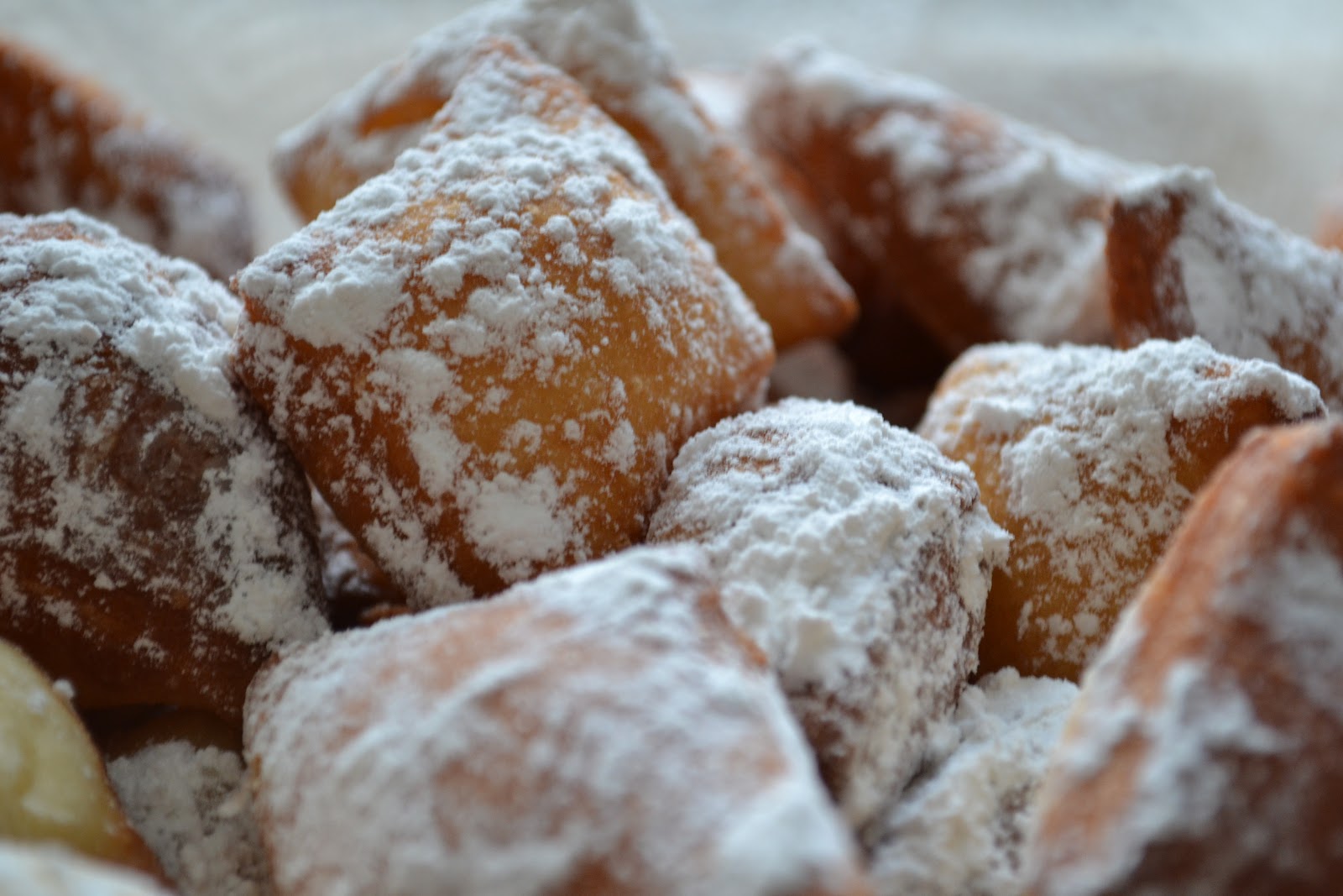 Fresh New Orleans beignets piled high under a heavy dusting of powdered sugar
