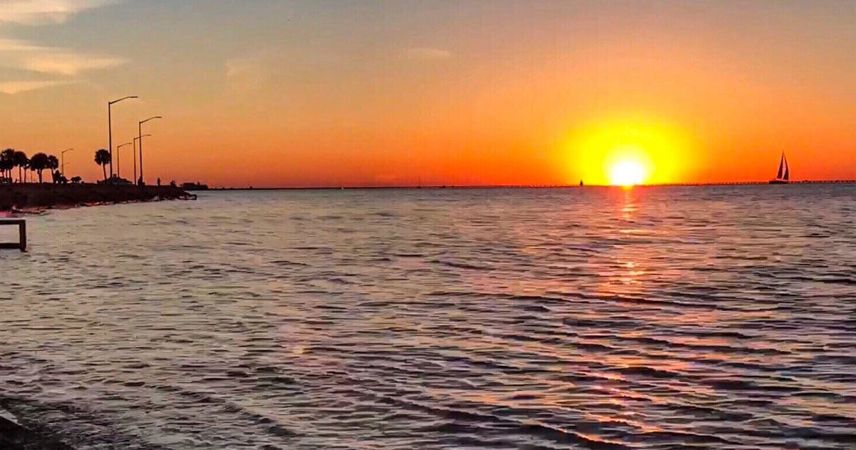 Fiery sunset over Lake Pontchartrain with a distant sailboat near New Orleans